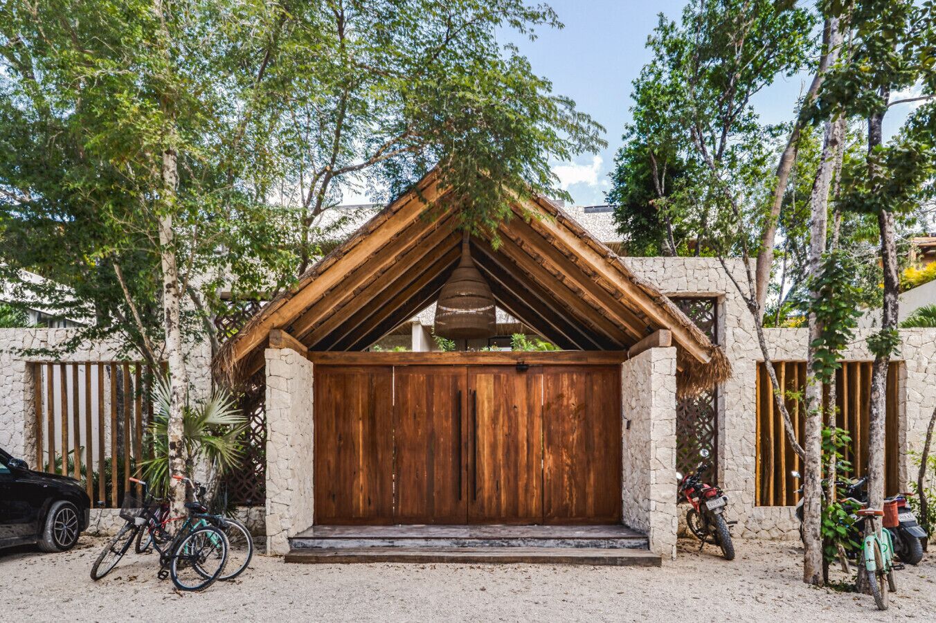 Une construction rustique en bois, dotée d’un toit en pente, entourée d’arbres et d’un mur de pierres.