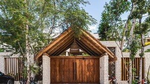 A rustic wooden structure with a sloped roof, surrounded by trees and a stone wall. - Jungle Luxury: 1-BR, Plunge Pool, Fully Equipped (Tulum)
