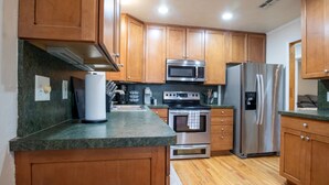 Una cocina con armarios de madera, un refrigerador de acero inoxidable, un microondas y un horno.