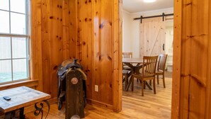 Una habitación con paneles de madera, una mesa y sillas, un perchero y una puerta corrediza tipo granero que da a otra habitación.