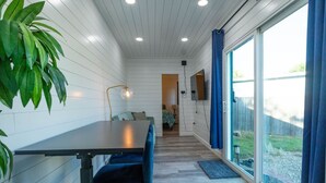 A modern interior with a dining area, a TV, and a view of the outdoors. - Container-Home 15 mins from FWTX | Pets Welcome (Fort Worth)