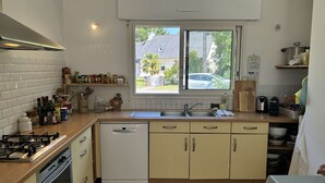 A kitchen with a window, a sink, cabinets, a stove, and a dishwasher. - Large family house for 11 guests near the beach in Fréhel | Ref 113 (FREHEL)