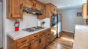 A kitchen with wooden cabinets, a stainless steel range hood, a gas stove, an oven, and a refrigerator. - Yosemite Aviary - Bird's Eye View! Awesome Upper Unit! (Yosemite National Park)