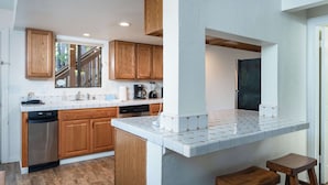 Una cocina moderna con armarios de madera, encimera blanca y una isla integrada con taburetes.