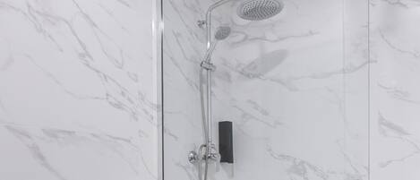A bathroom with a glass-enclosed shower, a white toilet, and marble-patterned walls.