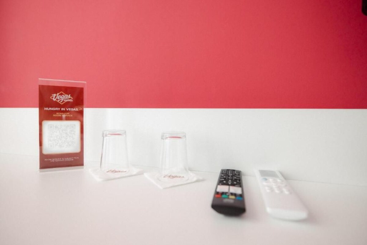 A remote control, a box, and two clear glass stands on a white surface.