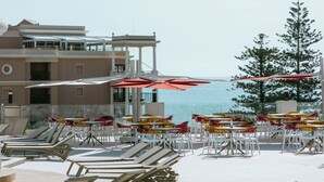 Un espace aménagé au bord de la piscine, avec des chaises longues, des parasols et une vue sur la mer.