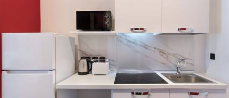 A modern kitchen with a microwave, toaster, kettle, and sink.