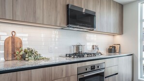 A modern kitchen with wooden cabinets, a stainless steel range hood, and a built-in oven.