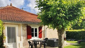 A house with a tiled roof, a front door, and a small patio with a table and chairs.