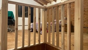 Une pièce avec un plafond en bois et une vue sur une chambre à coucher, où l’on aperçoit des lits et une nappe verte.