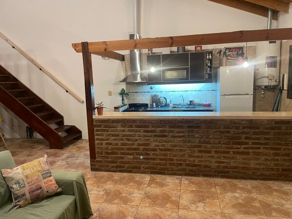 A kitchen with a brick counter, a stove, and a refrigerator.