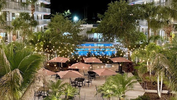 Une cour d’hôtel avec des espaces de détente en plein air, des palmiers et un espace piscine.