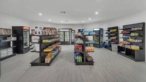 Une épicerie propre et bien éclairée, avec des étagères remplies de divers produits et un présentoir réfrigéré.