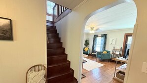 A wooden staircase leading to a living area with a sofa, a coffee table, and a TV.