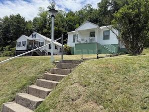 A residential area with a set of concrete steps leading to a house with a green exterior and a white roof.