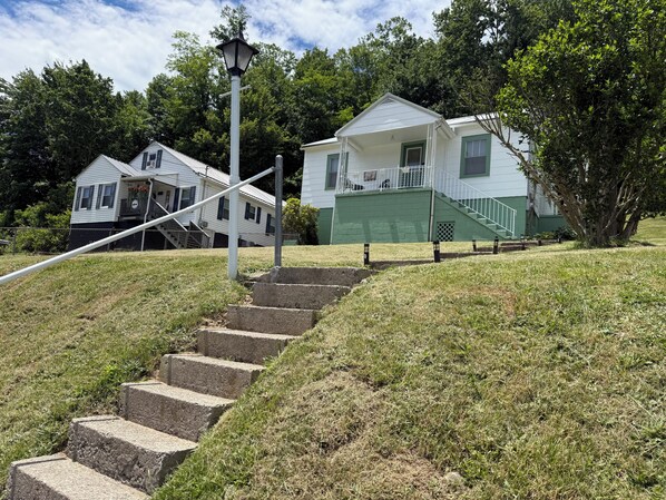 A residential area with a set of concrete steps leading to a house with a green exterior and a white roof.