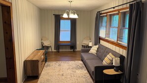 A cozy living room with a sofa, two chairs, a wooden bench, a small table, and a patterned rug.