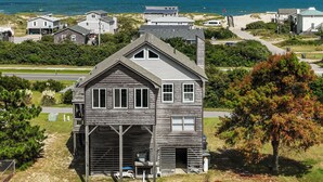 A coastal house with a garage, a covered porch, and a view of the beach and ocean.