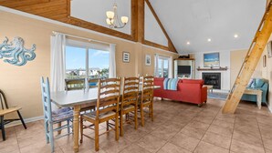 A spacious living area with a dining table, wooden chairs, a red sofa, and a fireplace.