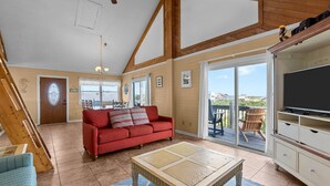 A spacious living room with a red sofa, a coffee table, and a TV on a cabinet.