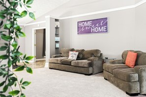 A living room with two sofas, a wall sign, and a plant. - Beautiful 3bd/2ba peaceful home in Lawrenceville with Gym, Office, and Jacuzzi (Lawrenceville)