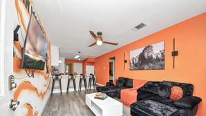 A modern living room with a black sofa, white coffee table, and orange walls.