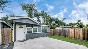 A single-story house with a front door, a garage, and a fenced backyard.