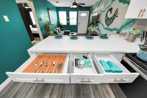 A modern kitchen with a central island, white cabinetry, and teal walls. - 2 Homes | Sleeps 8 | Gated Parking | 4BD/2BA |NRG (Houston)