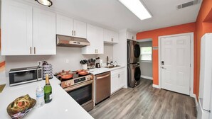 Eine moderne Küche mit weißen Schränken, Edelstahlgeräten und Holzboden.