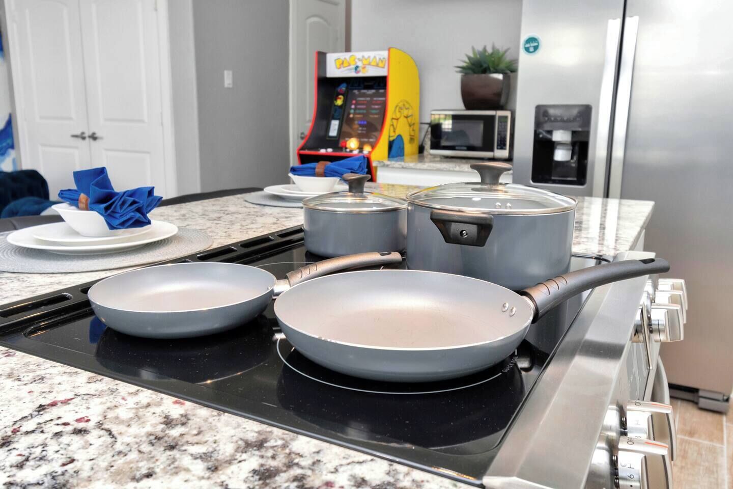 A kitchen with a stove, pots, pans, a microwave, and a coffee machine.