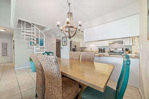 A modern kitchen with white cabinets, a built-in stove, and a dining area with wicker chairs and a wooden table.