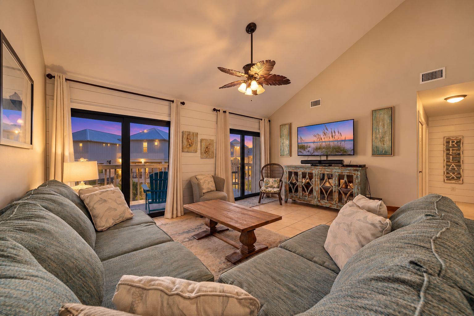 A living room with a sofa set, a coffee table, a television, and a ceiling fan.