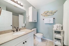 A bathroom with a double sink vanity, a toilet, a towel rack, and a decorative fish wall art piece.