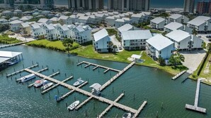 A marina with docked boats, a waterway, and a row of modern residential buildings with flat roofs.