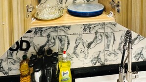 A kitchen with marble backsplash, wooden cabinets, and a sink with a faucet. - Magnificent T3 near the airport (Cotonou)