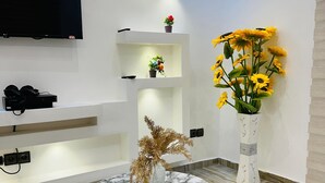 A modern interior with a marble table, a mounted TV, and decorative plants. - Magnificent T3 near the airport (Cotonou)