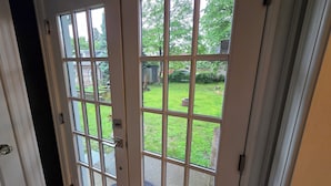 A double glass door with a view of a well-maintained lawn and a wooden fence. - 3-bedroom house in charming College Hill, Easton, PA with WiFi, AC. Book now (Easton)