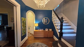 A staircase with a black handrail and white steps, leading to a landing area with a wooden console table and a mirror. - 3-bedroom house in charming College Hill, Easton, PA with WiFi, AC. Book now (Easton)