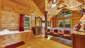 Une chambre dans une cabane en bois, avec un grand lit, une coiffeuse et un ventilateur de plafond.