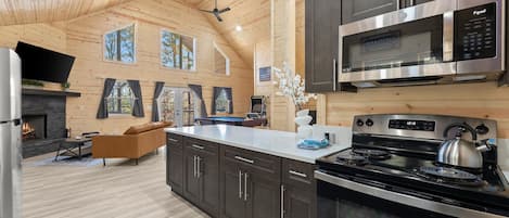 A modern kitchen with a large island, stainless steel appliances, and a fireplace.