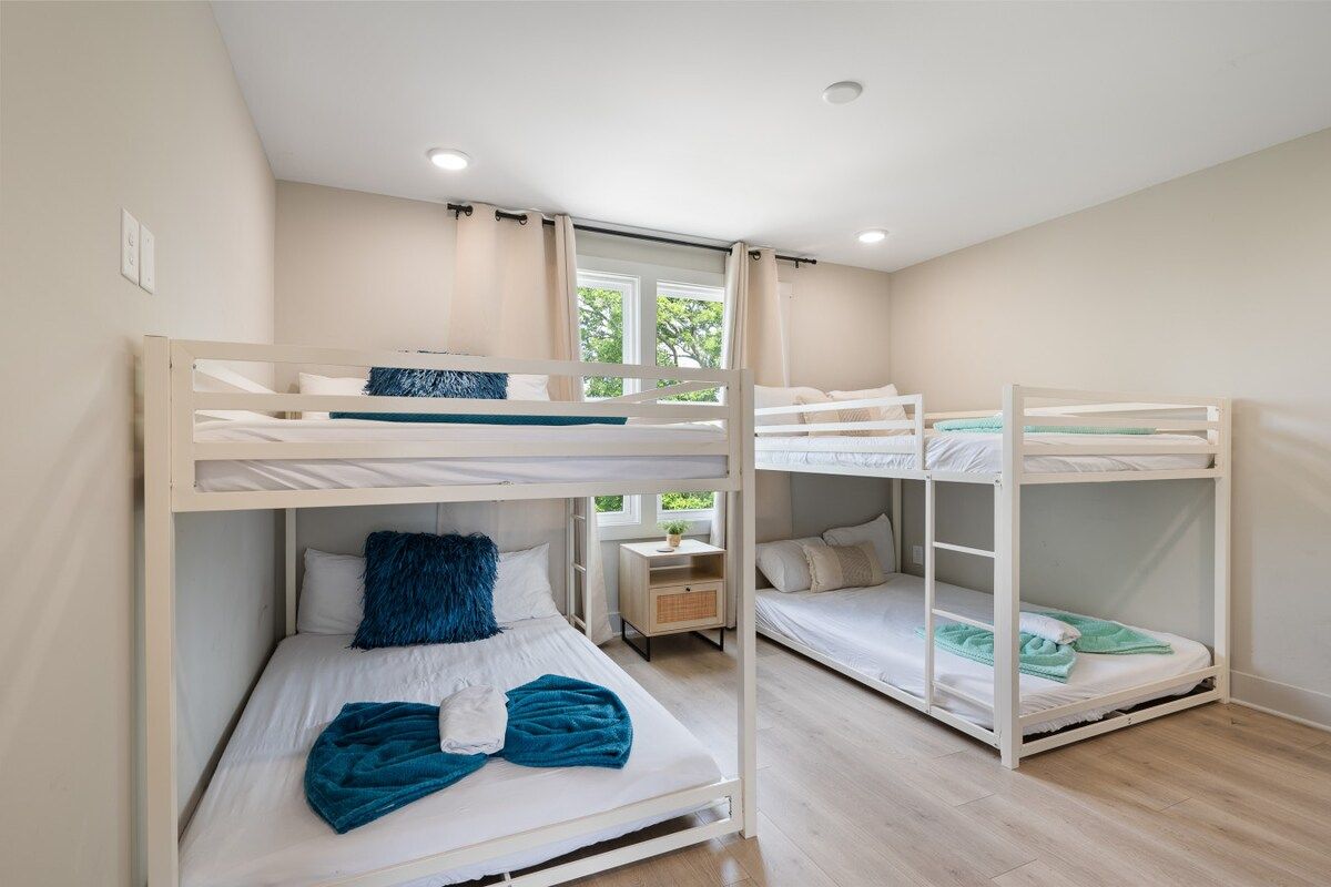 A bunk bed room with a window, a bedside table, and a nightstand.