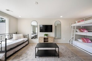 A bedroom with a bed, a desk, a TV, a mirror, and a bunk bed.