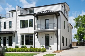 A modern two-story building with a flat roof, large windows, and a balcony.