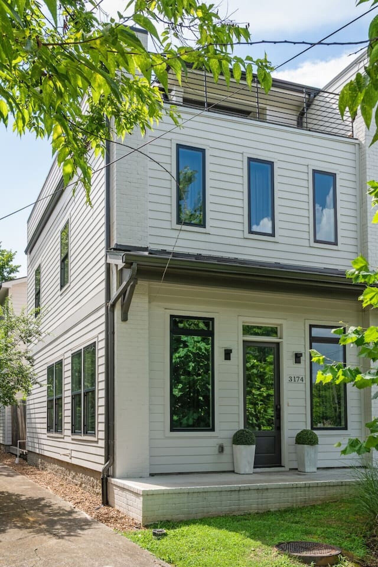 A two-story residential building with a front porch, large windows, and a visible address number.