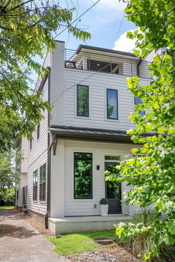 A two-story house with a front porch, large windows, and a visible garage door.