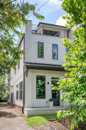 A two-story house with a front porch, large windows, and a visible garage door.