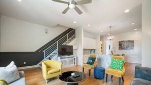 A modern living room with a sofa, armchairs, a coffee table, and a TV. - 16 Bed Private Gulch Home with Rooftop (Nashville)
