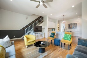 A modern living room with a sofa, armchairs, a coffee table, and a TV. - 16 Bed Private Gulch Home with Rooftop (Nashville)