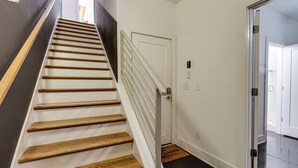A staircase with wooden steps and white railings leading to a white door with a doormat. - 16 Bed Private Gulch Home with Rooftop (Nashville)